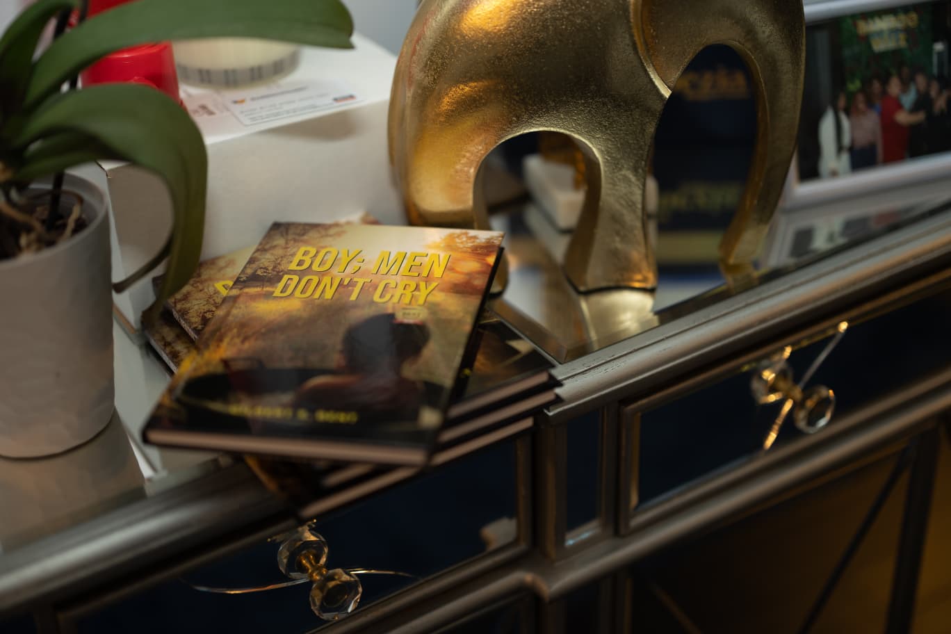 Still life of Boy, Men Don't Cry paperback among a collection of books